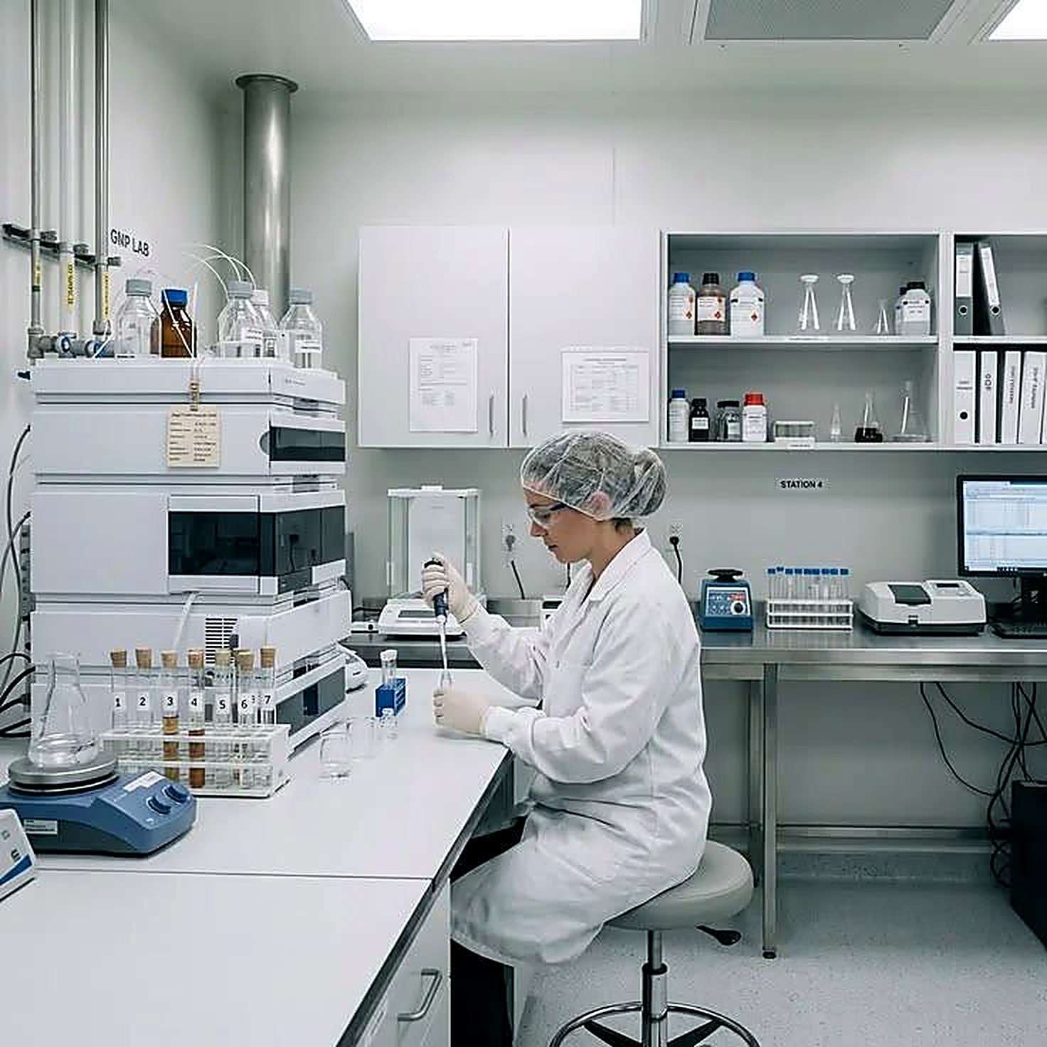 An analyst using a pipette beside analytical chromatography instrumentation